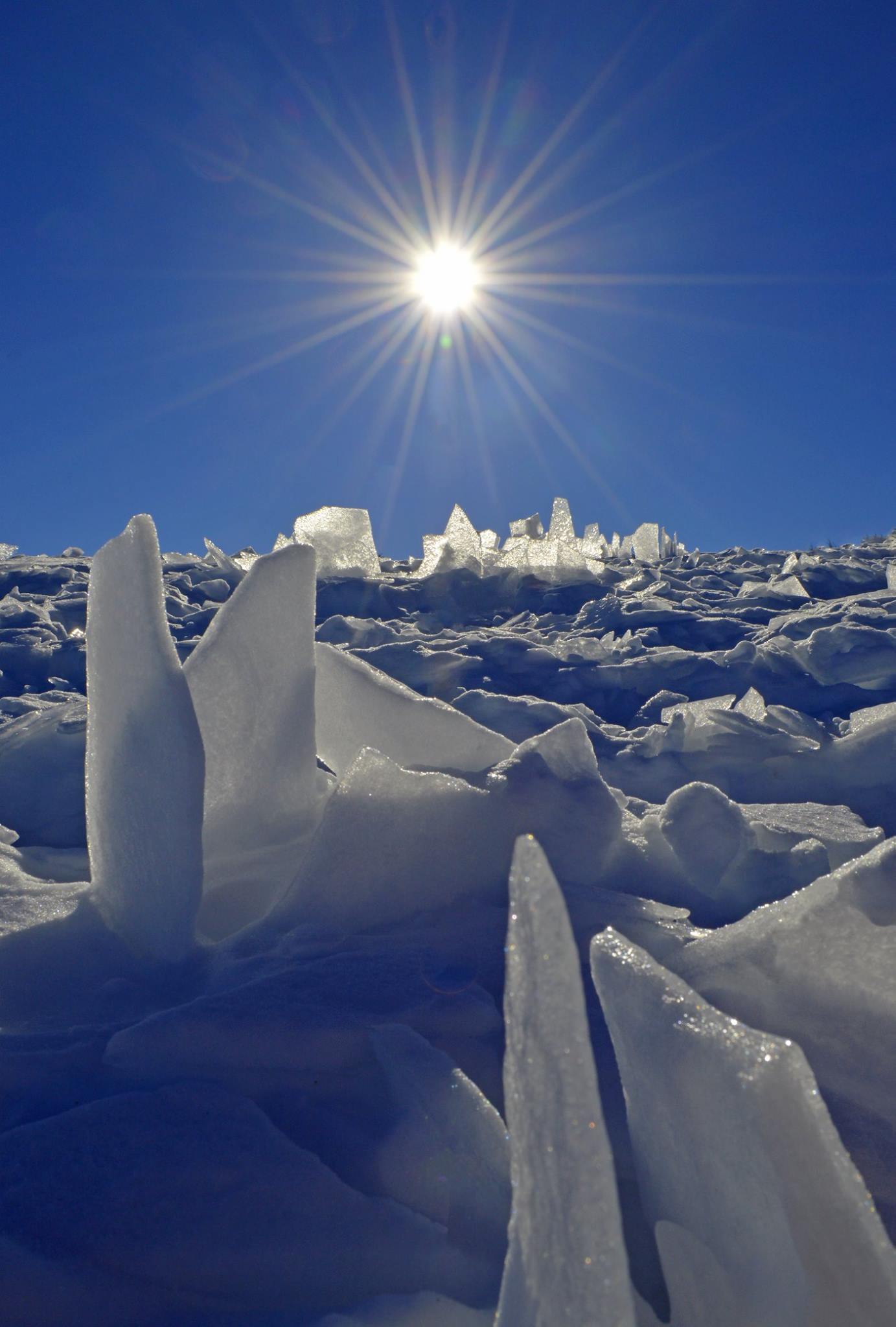 Eisfeld mit hochstehenden Kristallen vor blauem Himmel mit strahlender Sonne Eisfeld mit hochstehenden Kristallen vor blauem Himmel mit strahlender Sonne